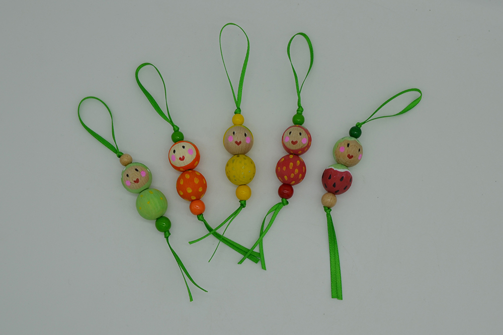 Gebastelte bunte Früchte aus jeweils vier kleinen Perlen mit grünem Bändchen zum Aufhängen